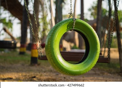 Color old car tire hanging on tree at playground