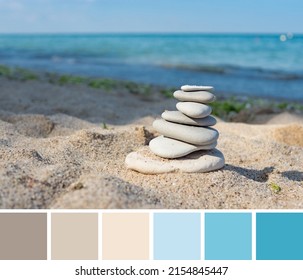 Color palette swatches of flat pebbles pyramid stack on beige brown sand on sunny beach and turquoise blue blurred sea water background. Pastel trendy combination, colorful inspiration from nature.