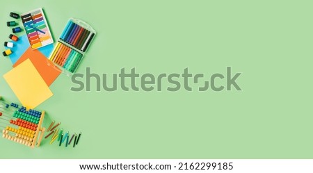 Color paper, paint and school stationery on green desk