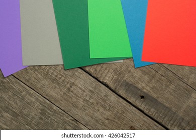 Color papers geometry flat composition on wooden background.