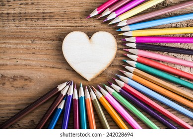 Color pencils around wood texture heart shape on background Empty space idea of concentration attraction to nucleus center circle radius unity concept of leadership community, team focused on one goal - Powered by Shutterstock