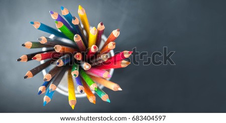 Variety, hand with coloured pencils against a green background