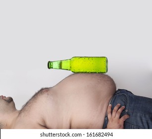 Color photo of a fat man with a green bottle full beer lie on belly Copy space for inscription 