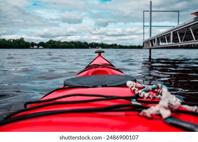 Color Photograph of a red Kayak on a the Mississippi River next to a dock on a cloudy day.
 - Powered by Shutterstock