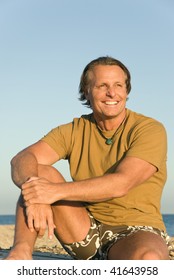 A Color Portrait Of A Happy Smiling Mature Man In His Forties Sitting On Beach.