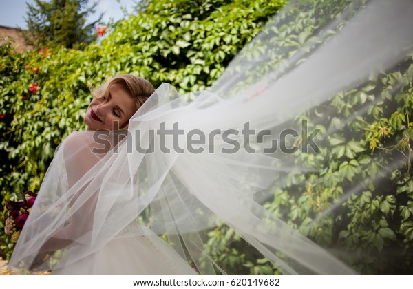 Color portrait\
of a smiling bride. Happy gorgeous bride smiling in the daytime.\
Sensual emotional moment of a luxurious wedding, young bride. Happy\
bride on vineyard\
background