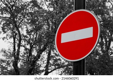 Color road traffic sign Entry is prohibited on back and white background of sky and trees foliage. Sign is also known as ''The Brick''. It restricts vehicles movement in this direction. - Shutterstock ID 2146060291