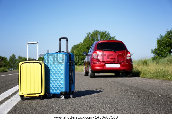 Color suitcases near family car on highway.\
Summer vacation