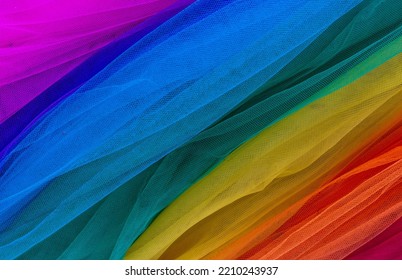 Color tulle material. Tulle material lined diagonally in rainbow colors. Cheerful, rainbow-effect background, tulle cloth fabric textura