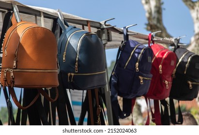 colored bags or backpacks hanging on street market stalls