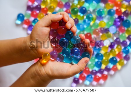 Colored balls of hydrogel in children's palms. Sensory experiences
