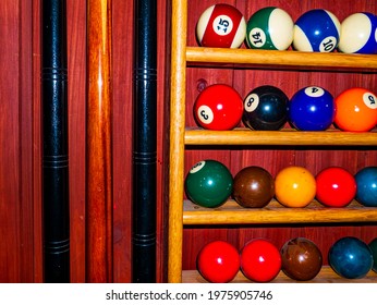 Colored Billiard Balls And A Cue On A Wooden Shelf. Billiard Ball. Wooden Shelf. Numbered Balls. Gambling. Sports Game. Leisure Activities. Business. Background Image.