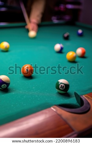 colored billiard balls with numbers on the billiard table in front of the pocket.