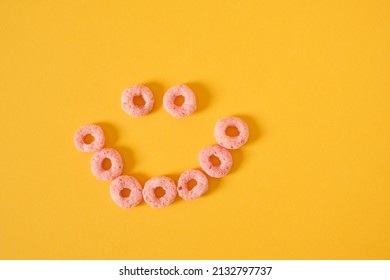 colored breakfast cereals laid out in the shape of a smiley face on a yellow background top view, children's healthy breakfast - Powered by Shutterstock