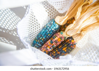 Colored Bright Corn In A Shopping Mesh Bag. Fancy Food, Dry Popcorn Product. White String Bag On A White Table On A Bright Sunny Day.
