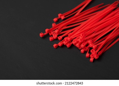Colored, bright, red, plastic cable ties on a black background. place for the inscription.