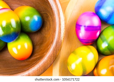 Colored by hand Easter eggs in a natural oak and ipe wood bowls isolated on a wood counter top board close up