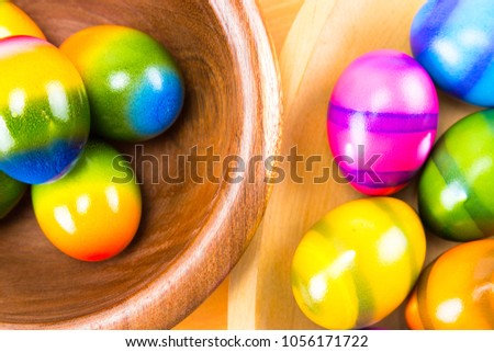 Colored by hand Easter eggs in a natural oak and ipe wood bowls isolated on a wood counter top board close up