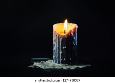 colored candle with drips of wax burns in the dark on a black background in smoke with dripping wax - Powered by Shutterstock