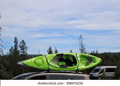 Colored Canoe Strapped To A Roof Rack On Top Of A Car