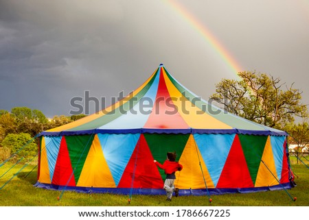 Colored circus tent in a rainy day with a rainbow on the sky