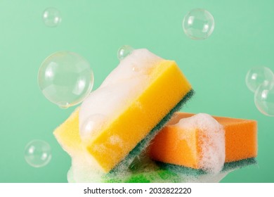 Colored Cleaning Sponges with Bubbles and soapy Foam on green background. Wet Kitchen Dishwashing Sponge with copy space. - Powered by Shutterstock