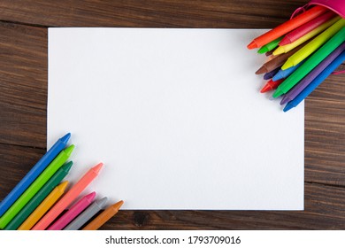 Colored Crayons And Blank Page On The Wooden Table