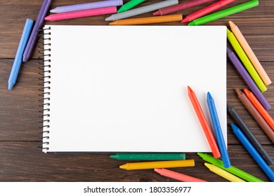 Colored Crayons And Blank Page On The Wooden Table