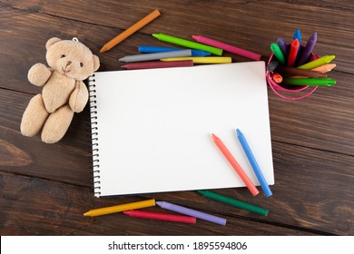 Colored Crayons And Blank Page On The Wooden Table