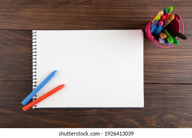 Colored Crayons And Blank Page On The Wooden Table