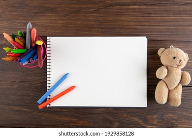 Colored Crayons And Blank Page On The Wooden Table