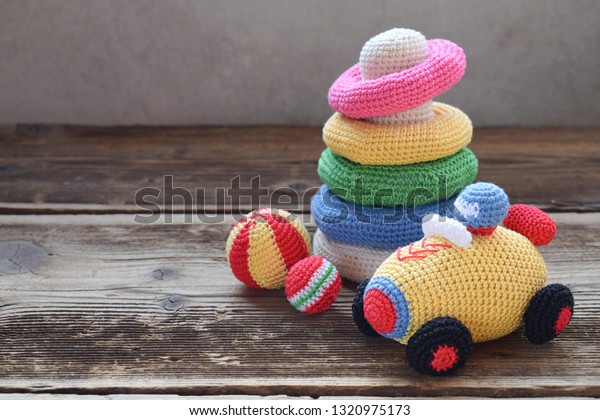 Colored crochet racing car and\
pyramid from colored rings. Toy for babies and toddlers to learn\
mechanical skills and colors. Handmade crafts. DIY\
concept.
