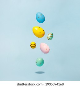 Colored easter decorated eggs flying on a blue background. Easter greeting card in minimalist style concept.Copy space