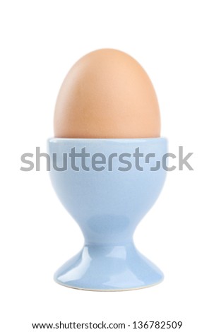 Colored easter egg in blue egg cup, isolated on white. Traditional symbol of the feast