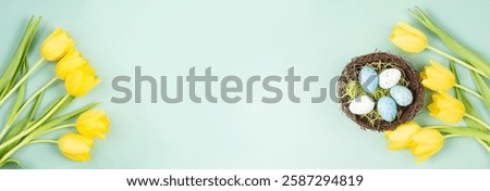 Colored easter eggs in a bird wicker nest, yellow tulip flowers, holiday greeting card, spring season background 