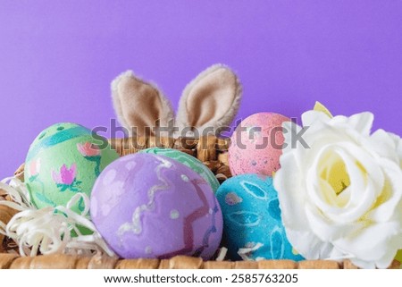 Colored Easter eggs and funny bunny in purple background .Copy sapce.Wallpaper for Easter announcements and cards.Horizontal real picture.
