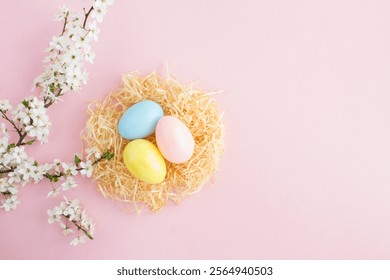 Colored easter eggs in a nest of straw and white flowering tree branches on the pink background. Top view. Copy space. - Powered by Shutterstock