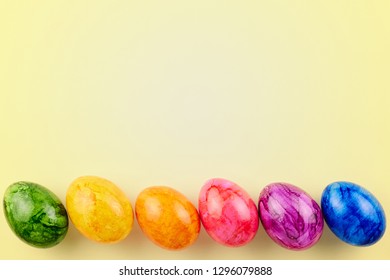 Colored Easter eggs on yellow background. Flat lay, top view with copy space