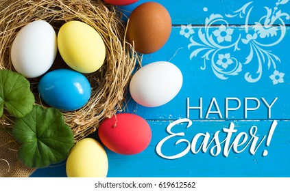 Colored eggs in nest on wooden background, selective focus image. Happy Easter Card