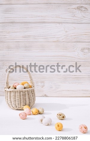Colored eggs in a straw basket on a wooden white background. Symbol of the Easter holiday. Easter background. Front view
