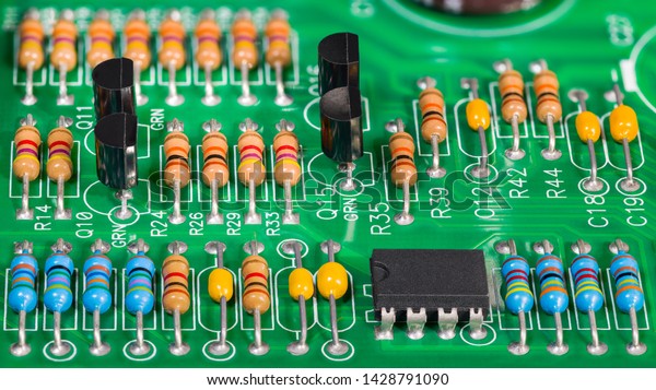 Colored electronic components. Resistors,\
transistors, capacitors and integrated circuit on PCB. Standard\
color code. Green copper board detail. Dismantled computer\
hardware. Electrotechnics,\
e-waste.