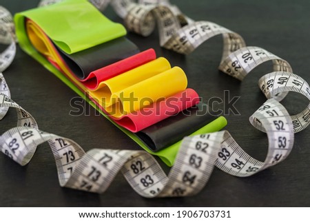 colored fitness rubber bands and twisted measuring tape on black. Healthy lifestyle.