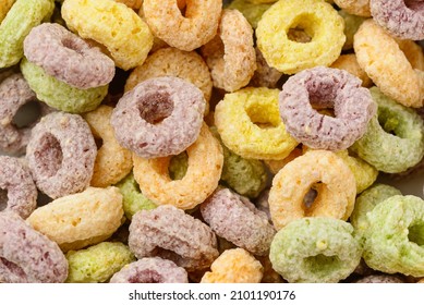Colored flavored cereal rings as texture or food background. Closeup of funny breakfast cereals - fruity loops or fruity hoops 