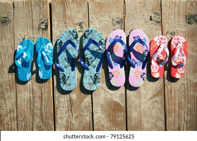 Colored flip-flops of a family of four by the beach at the ocean