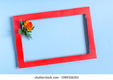 A Colored Frame Decorated With An Orange Flower On A Blue Background Of The Mine Space. Flat Lei Bright Red Paper Frame And Floral Decor