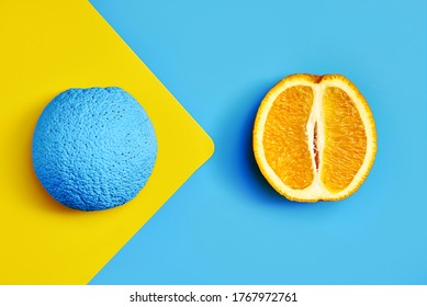 colored and fresh orange cut in half. blue yellow background. design. creative