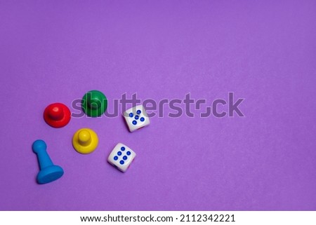 Colored game chips and playing cubes laid out on a purple background: entertainment, games at home for the whole family, the concept of board games. Board game. Table games