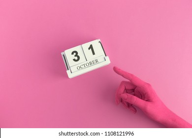 Colored Hand Showing 31st Of October Date On Wooden Calendar. Halloween Pink Minimal Creative Holiday Concept.