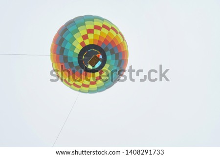 Colored hot air balloon on light sky background bottom-up view. Festival hot air balloons. Multicolored balloon in the sky close-up