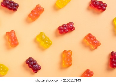 Colored jelly bears on an orange background. Top view.